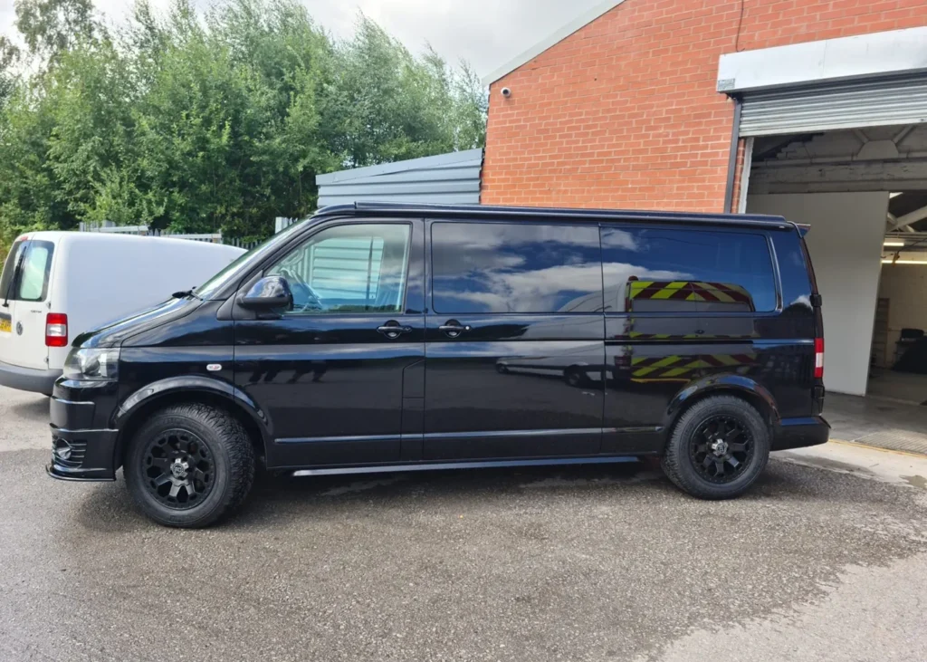 Black camper van conversion parked outdoors, representing Hawke Vans’ modern camper solutions in Manchester