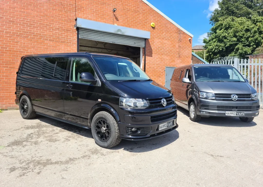 Black and grey camper vans parked outside, designed with functionality and modern aesthetics by Hawke Vans