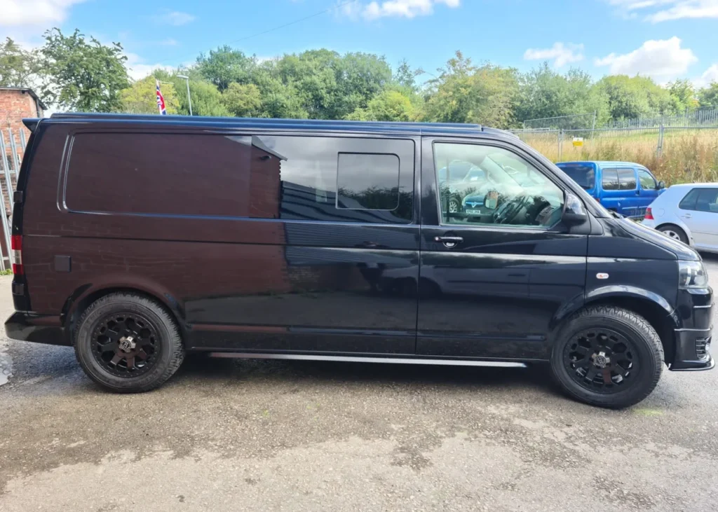 Black camper van parked outdoors, reflecting Hawke Vans’ dedication to quality and adventure-ready designs