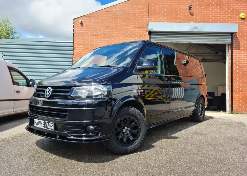 Black Volkswagen camper van parked outdoors, showcasing modern design and bespoke craftsmanship