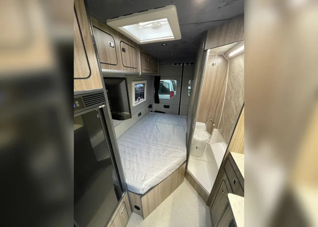 Camper van interior featuring a comfortable bedroom and a compact bathroom with modern amenities