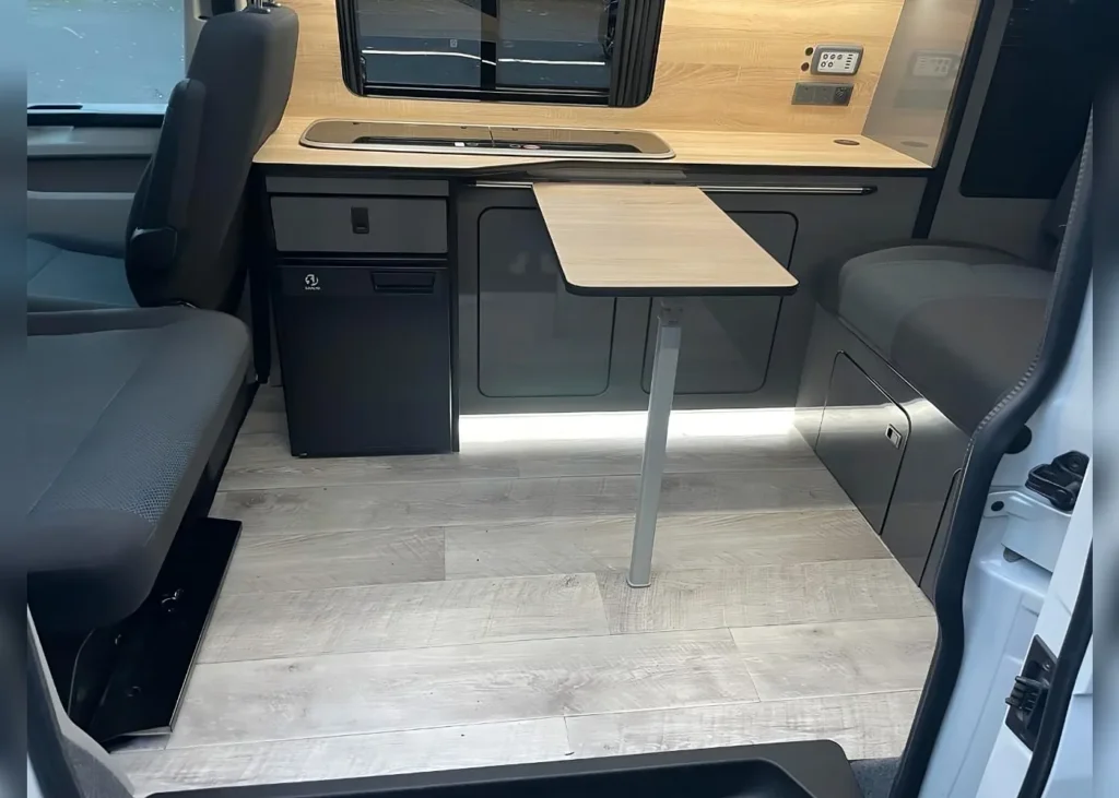 Modern camper van dining area with a small table and kitchen setup