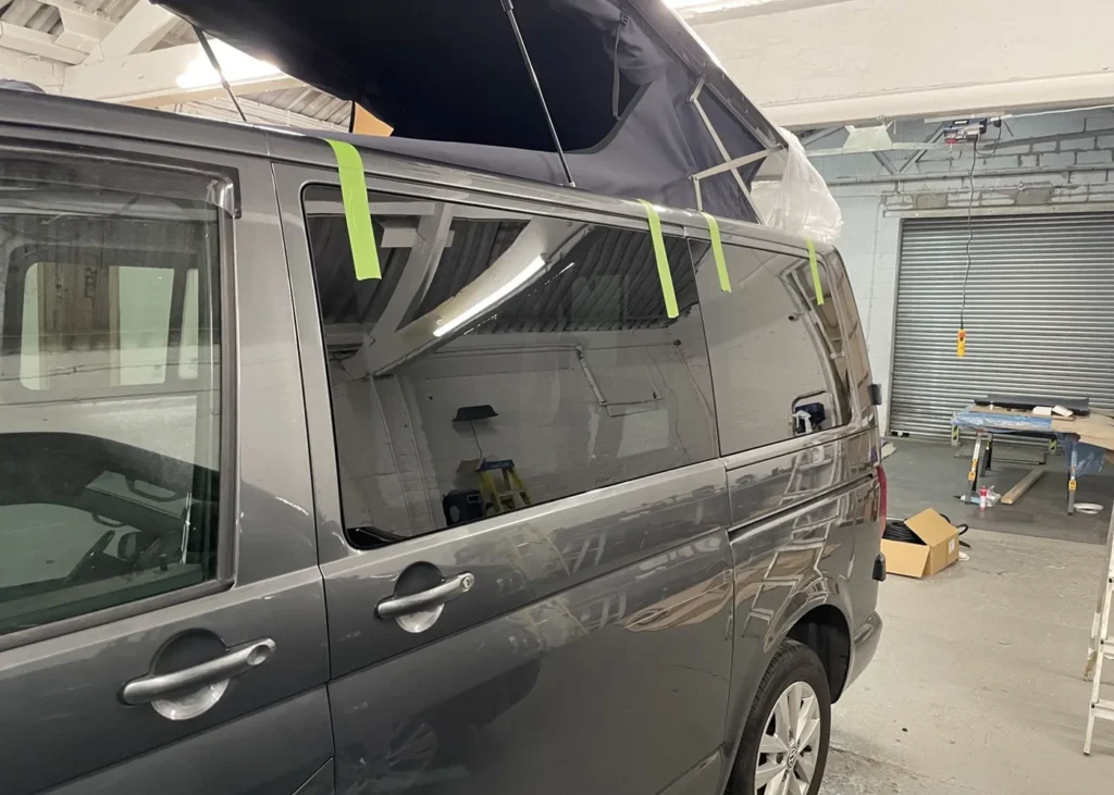 Grey camper van with a pop-up roof being installed, part of bespoke camper conversion projects in Manchester