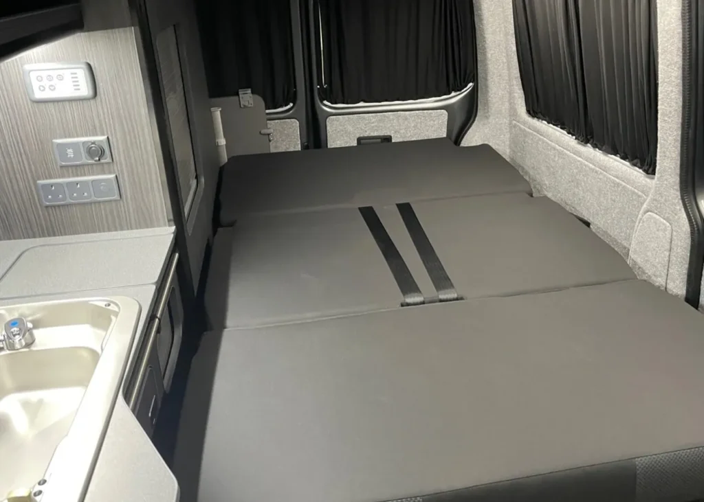 Camper van interior with a fold-out bed and kitchenette, designed for bespoke camper conversions in Manchester