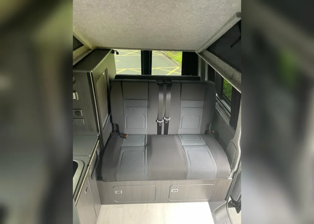 Camper van interior seating area with storage compartments