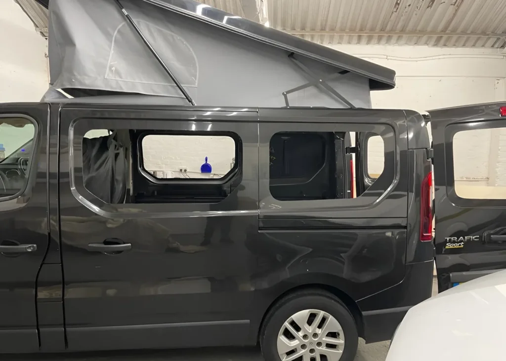 Grey camper van with a pop-up roof, shown before window installation as part of a bespoke camper conversion in Manchester