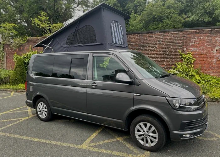 Grey camper van with an extended pop-up roof, parked outdoors