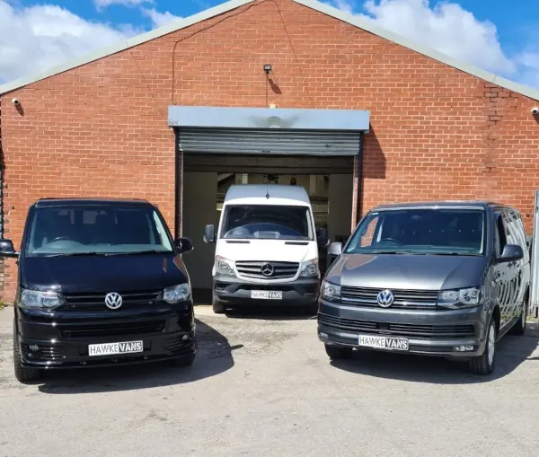 Three camper vans parked in front of a workshop