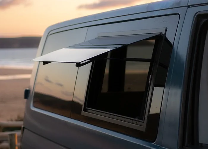 Camper van with an open side window, showcasing a sunset beach view