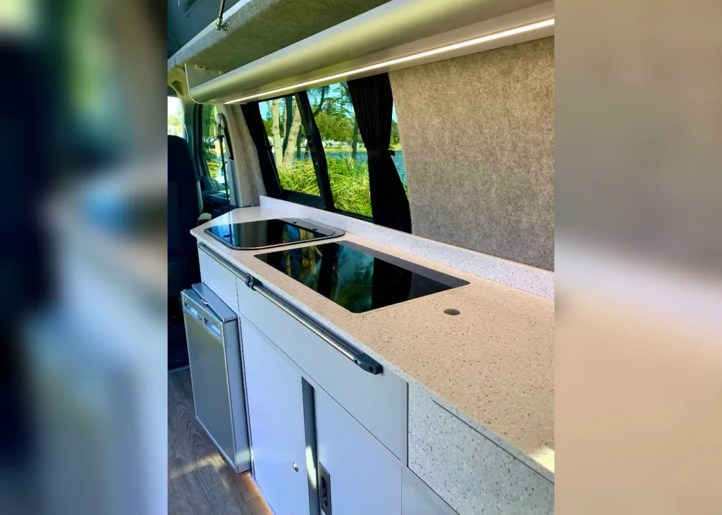 Modern camper kitchen with induction hob and compact sink.