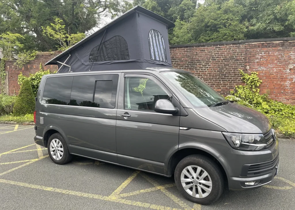 Grey camper van with extended pop-top roof parked outdoors