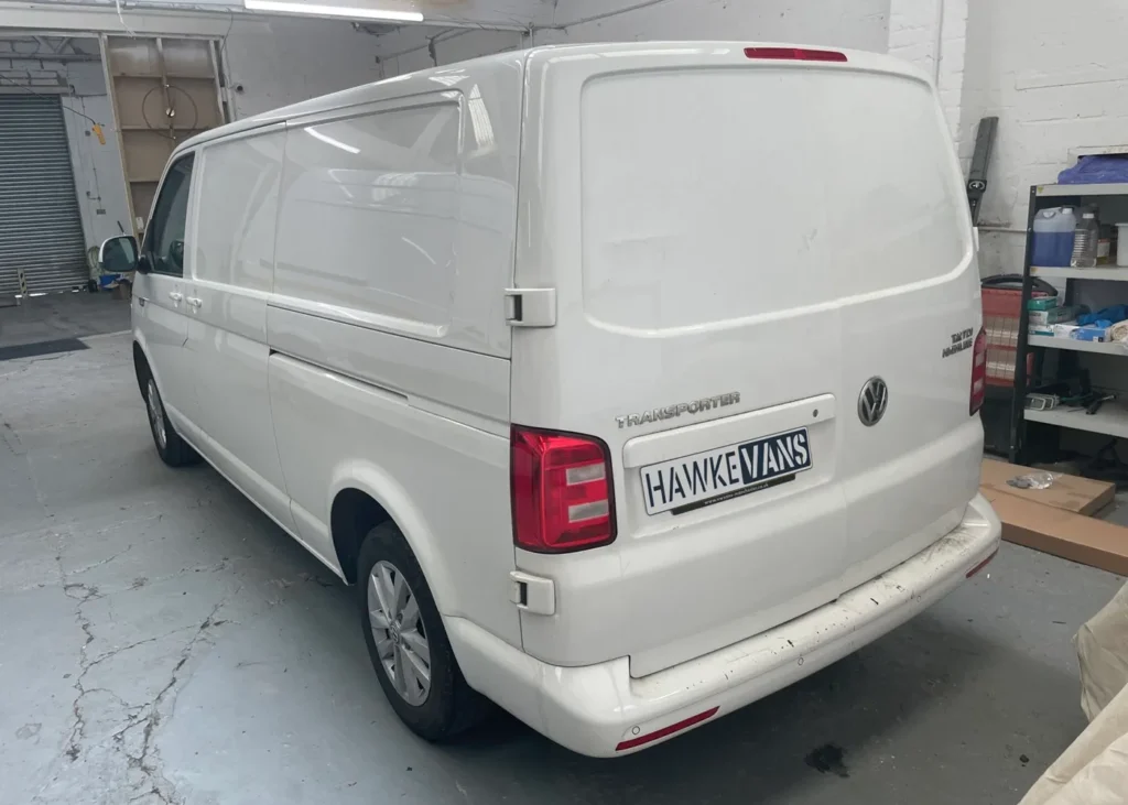 Rear view of a white camper van in a workshop