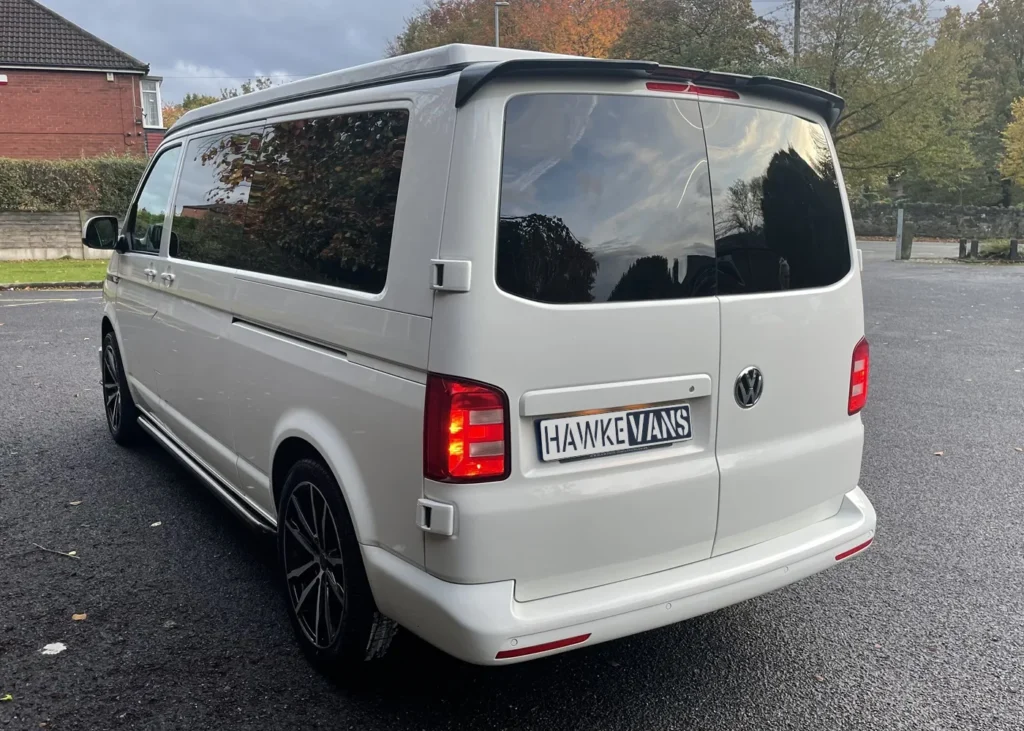 Rear side view of a white camper van with tinted windows