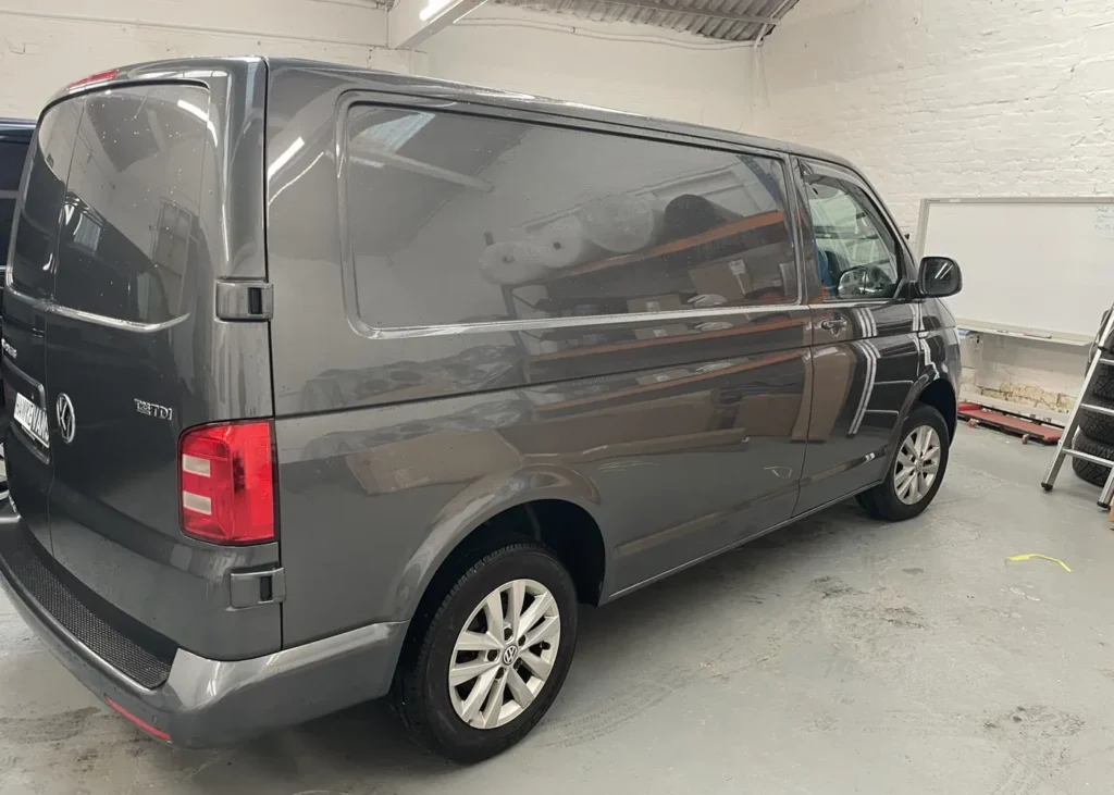 Side view of a dark gray camper van in a workshop