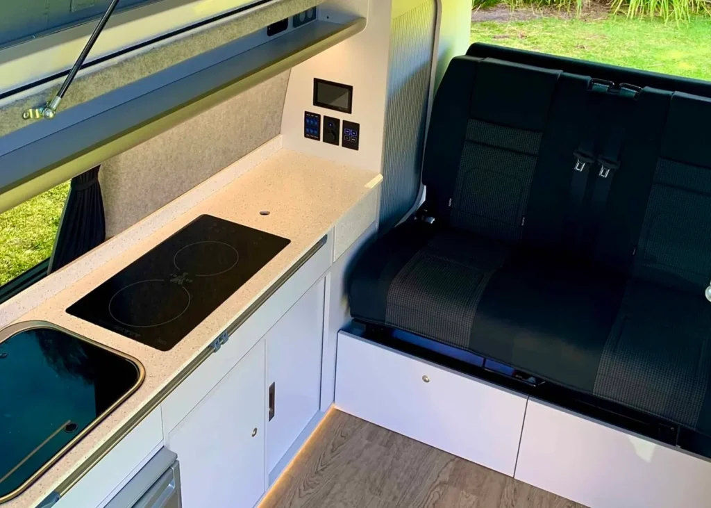 Compact camper kitchen with cooktop and seating area