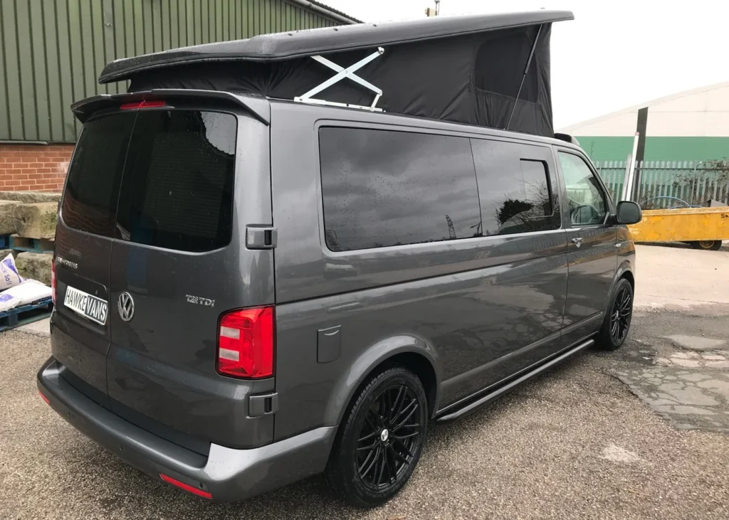 Grey Volkswagen camper van with a raised roof and black alloy wheels, rear and side view