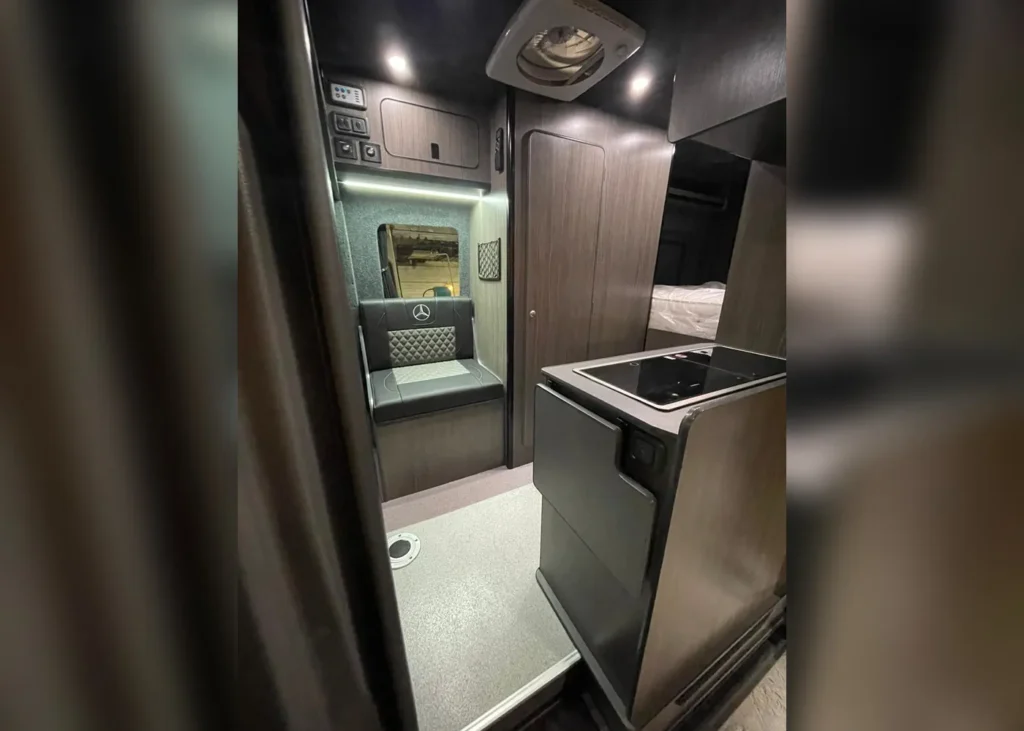 Interior of a Mercedes luxury camper van with premium leather seating, modern kitchenette, and ambient lighting