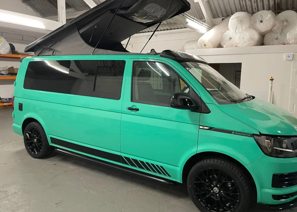 Mint green camper van with a black pop-up roof and sleek black detailing