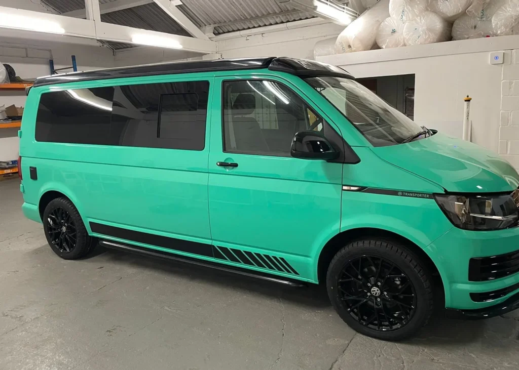 Mint green camper van with black accents in a workshop