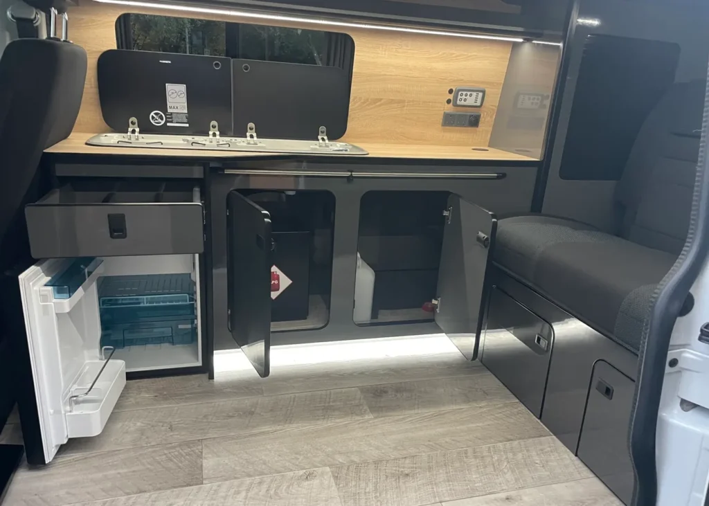 VW camper kitchen with open storage and fridge