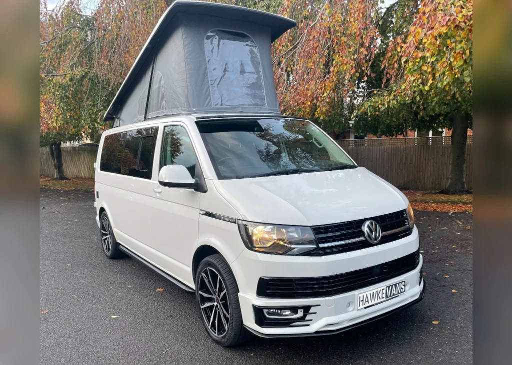 White camper van with extended roof in an autumn setting