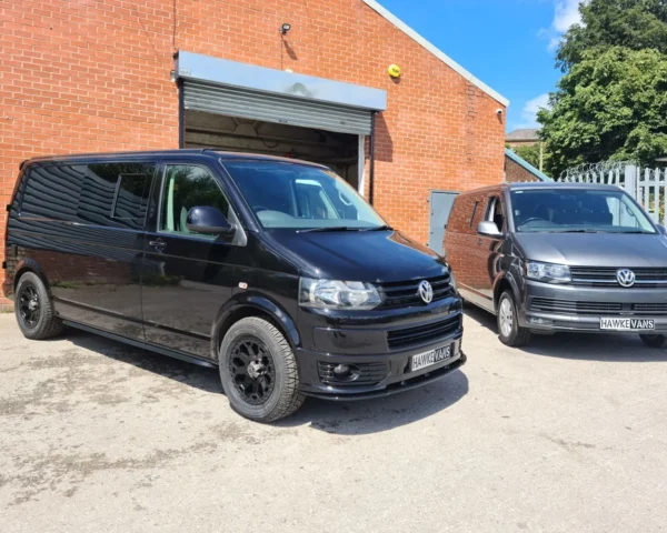 Black and grey camper vans parked outside, designed with functionality and modern aesthetics by Hawke Vans