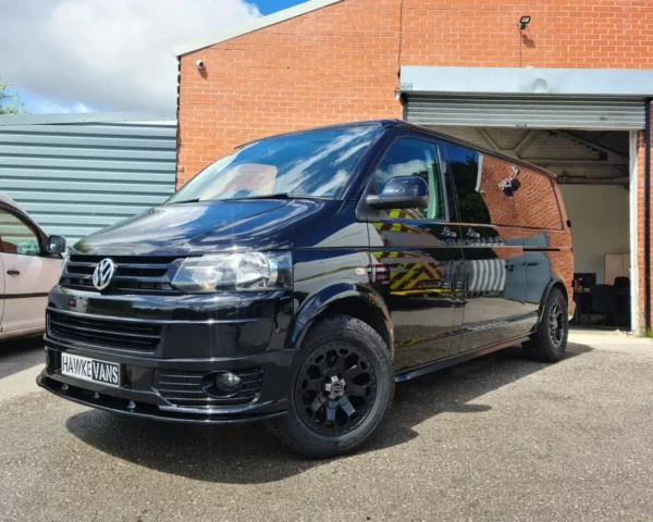 Black Volkswagen camper van parked outdoors, showcasing modern design and bespoke craftsmanship